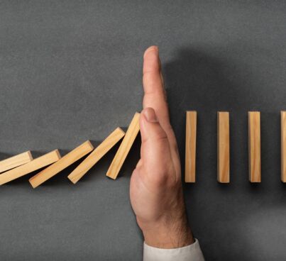 hand stopping falling dominoes as mood image for online risk management section