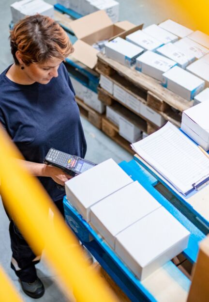 woman with a handheld scanner in a shipping center to visualize digital order fulfillment