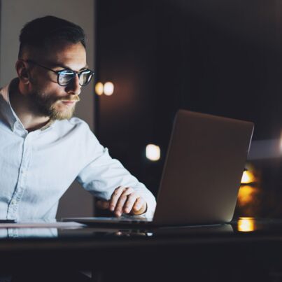 man working on a laptop in the dark as mood image for section digitization services